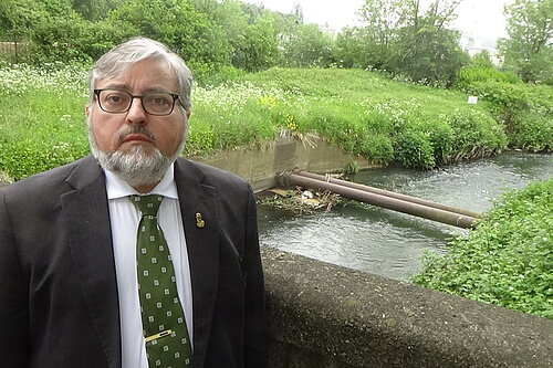 Cllr Ron Beadle next to polluted river Team